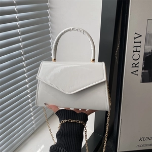 Minimalist white patent leather crossbody bag with top handle and gold chain strap