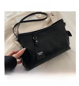 Detail of black leather shoulder bag with adjustable strap and side pocket for women