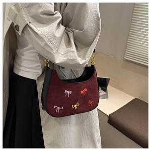 Détail du sac hobo en daim rouge avec broderies papillons colorées et bordures en cuir noir