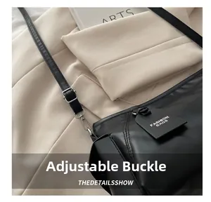 Detailed close-up of the adjustable silver buckle and strap on a black leather handbag