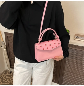 Detailed macro view of pink handbag with strawberry print and smooth leather texture