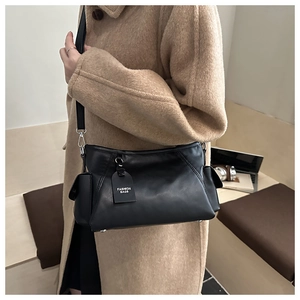 Detail of black leather shoulder bag with side pocket and decorative fashion tag