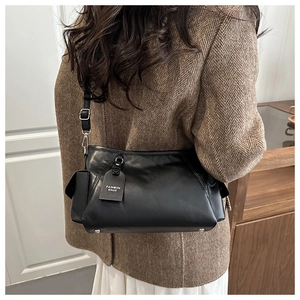 Detail view of large black commuter bag side pocket and adjustable strap worn on coat