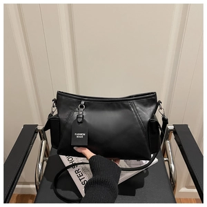 Close-up of matte black leather bag on a leather chair with a Fashion Bags decorative tag