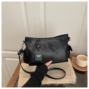 Detail of soft black PU leather crossbody bag with side pockets and fashion tag