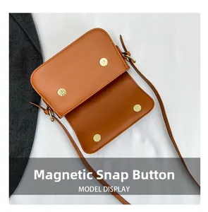Détail du sac bandoulière marron montrant le fermoir magnétique double et le cuir lisse