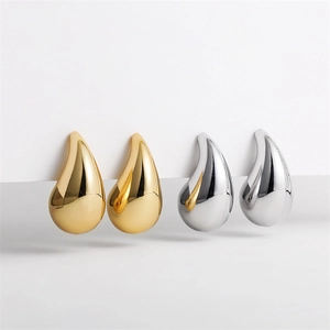 Macro detail of gold and silver teardrop earrings with a polished mirror finish