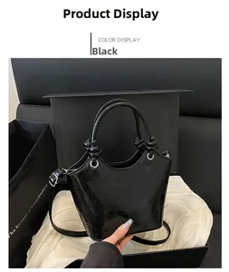 Detail of black glossy patent leather handbag with embossed patterns and knotted handles