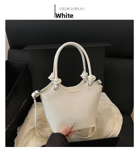 Detailed view of white bucket bag featuring embossed cartoon motifs and round top handles