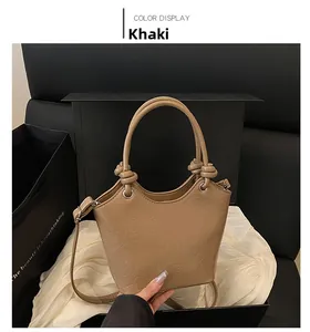 Detail view of khaki embossed bucket bag with heart patterns and knot handle