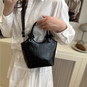 Black bucket bag with embossed cartoon patterns and dual handles in a lifestyle setting