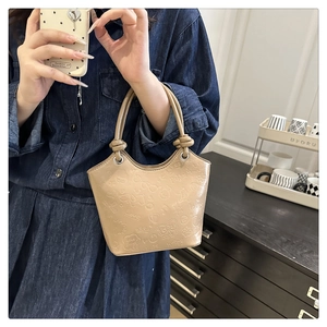 Detail of khaki PU bucket bag with cute cartoon embossing and knotted handles