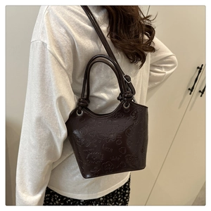 Detail of dark brown embossed leather bucket bag with adjustable strap and top handles