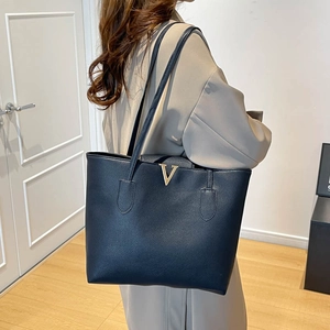 Detail of large tote bag in navy pebble leather with golden metal V logo decoration