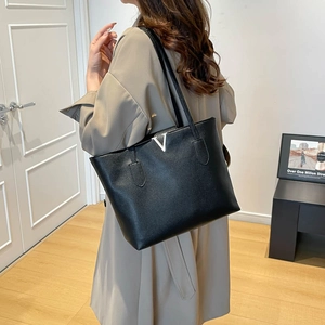 Black pebble leather tote bag with silver V hardware shown in a minimalist interior setting