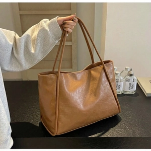 Detail view of large brown tote bag showing vintage leather texture and slim shoulder straps