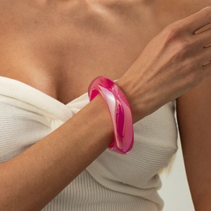 Nahaufnahme eines breiten, rosa-transparenten Harzarmreifs mit glänzender Oberfläche