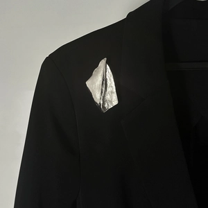Gros plan sur la broche argentée froissée irrégulière sur un revers de costume noir