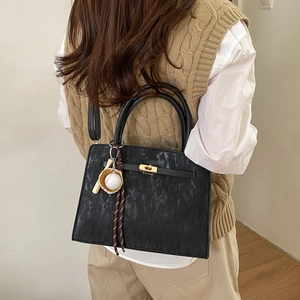 Elegant black vertical-stripe handbag with metallic lock and baseball theme bag charm