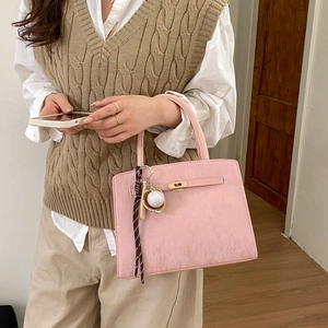 Detailed shot of pink leather Kelly style handbag with a decorative baseball keychain