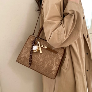 Detail of vintage brown textured tote with metal lock, silk scarf, and baseball charm