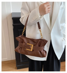 Détail du sac porté épaule marron avec boucle dorée et bandoulière chaîne sur modèle