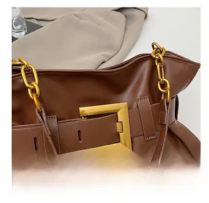 Gros plan d'une boucle carrée dorée et d'une chaîne sur un sac en cuir marron foncé