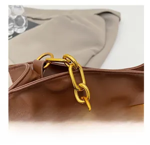 Détail d'une chaîne en métal doré sur un sac nuage vintage en cuir souple marron foncé