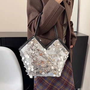 Silver sequin hobo bag with V-shaped opening and black leather handles shown on shoulder