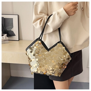 Close-up of golden sequins on a tote bag with black leather straps and V-shaped edge