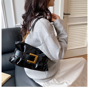 Détail du sac nuage plissé noir avec une boucle carrée dorée et une chaîne en métal