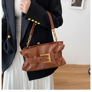 Gros plan d'un sac nuage plissé marron avec boucle dorée porté par un mannequin