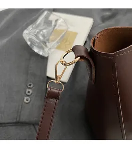 Detailed close-up of golden metal hardware on a vintage brown leather bucket bag