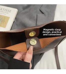 Detailed view of the gold magnetic closure on a dark brown leather bucket handbag