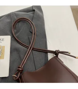Close-up of the knotted leather strap and smooth texture of the vintage brown tote bag