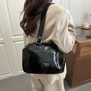 Glossy black wax leather tote bag with silver ring hardware shown on a model