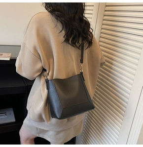 Close-up of black matte leather bucket bag with slim shoulder strap on model back