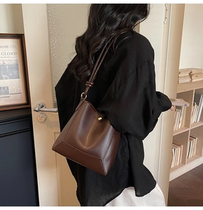 Detailed view of dark brown leather bucket bag with reinforced stitching and long shoulder strap