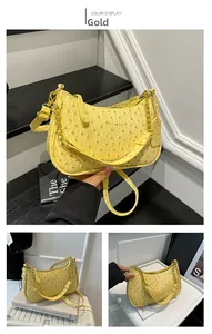 Detail of golden ostrich texture underarm bag with elegant chain and logo tag