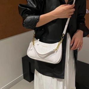 White ostrich texture underarm bag with gold chain strap shown on a model