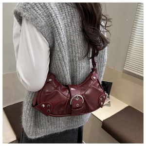 Detail of burgundy leather shoulder bag with vintage rivets and pleats worn by model
