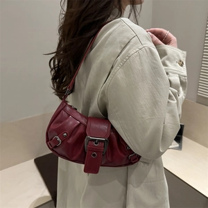 Vintage burgundy leather underarm bag with metal buckle shown on a khaki coat
