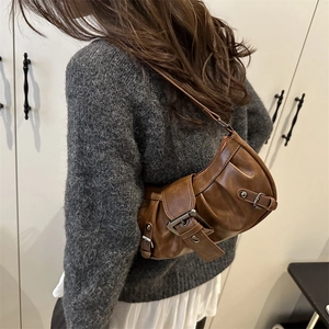 Retro brown leather shoulder bag with large metal buckle detail on a model