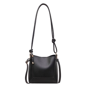 Minimalist black matte leather bucket shoulder bag with sleek gold hardware and knot detail