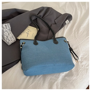 Blue denim tote bag with black leather straps and gold hardware on white fabric