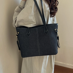 Minimalist black denim tote bag with white contrast stitching and gold hardware details
