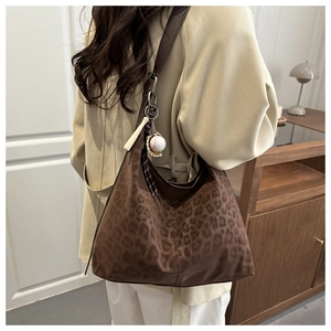 Macro view of leopard print hobo bag with baseball charm and suede texture