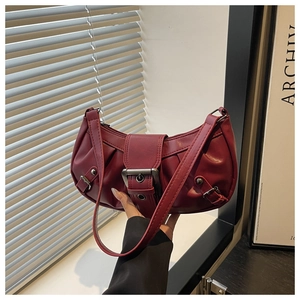 Detail of burgundy leather shoulder bag showing glossy pleated texture and metal buckle