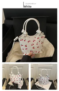 Dettaglio della borsa bianca con stampa ciliegie rosse e design del manico annodato