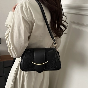 Minimalist large black crossbody bag with gold buckle shown on a model's shoulder